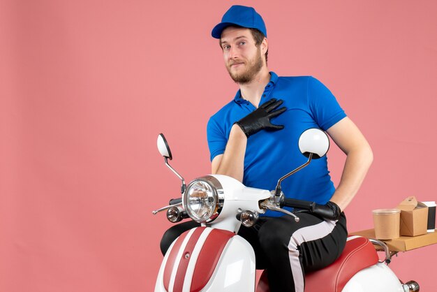 Corriere maschio vista frontale in uniforme blu e guanti su bici di consegna cibo servizio fast-food lavoro di colore rosa color