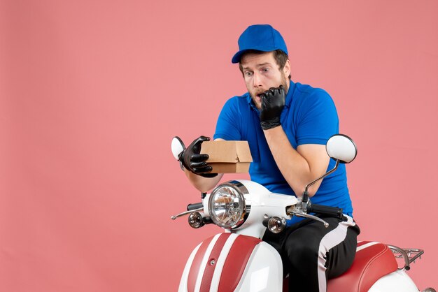 Corriere maschio vista frontale seduto in bici e con un piccolo pacchetto di cibo in rosa food