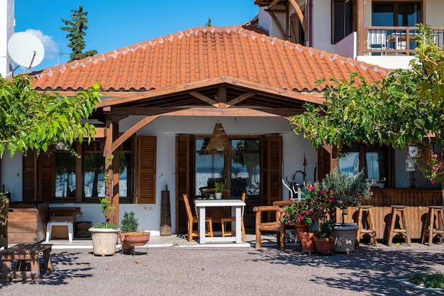 Cortile anteriore e terrazza di un ristorante realizzato in stile nazionale con vegetazione, sedie e tavoli a Nikiti, Grecia