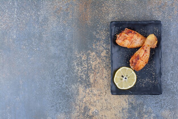 Cosce di pollo alla griglia sulla banda nera con il limone.