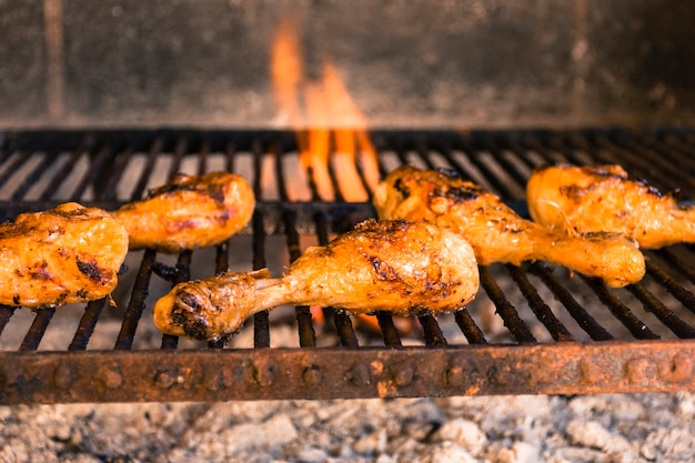 Cosce di pollo alla griglia sulla griglia calda con fuoco pesante