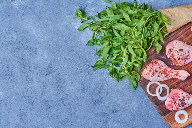 Cosce di pollo alle erbe su una tavola di legno sul blu