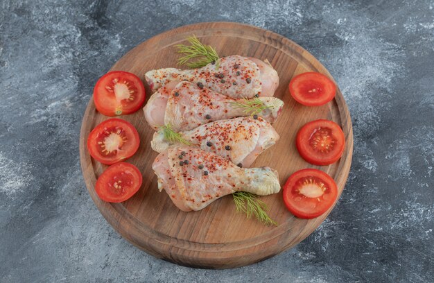 Cosce di pollo crude con spezie su un tagliere di legno. Pronto per preparare il pollo al curry.