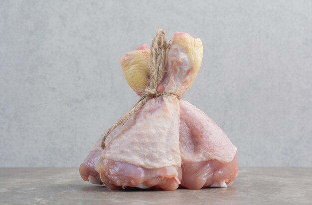 Cosce di pollo crude in corda su fondo di marmo. Foto di alta qualità