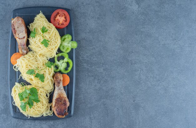 Cosce di pollo e spaghetti su tavola di legno.