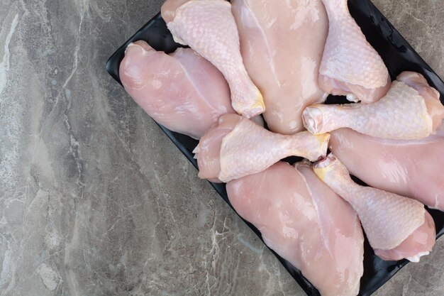 Cosce di pollo fresche non preparate sul piatto scuro. Foto di alta qualità