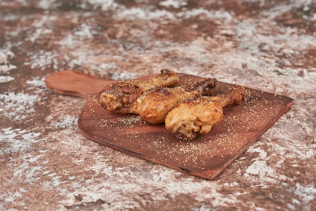 Cosce di pollo fritte su tavola di legno.