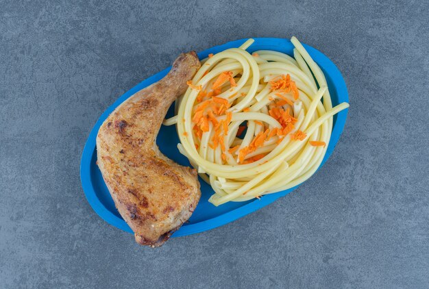 Coscia di pollo alla griglia e spaghetti sul piatto blu.