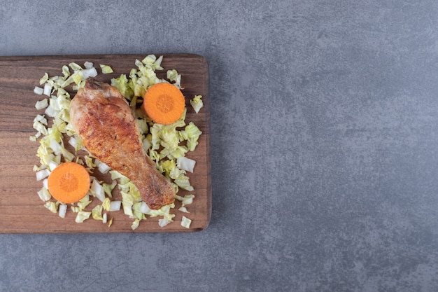 Coscia di pollo e verdure a fette su tavola di legno.