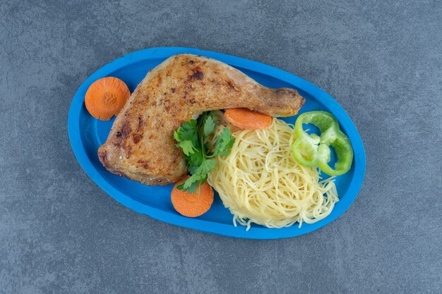 Coscia di pollo fritto e spaghetti sul piatto blu.