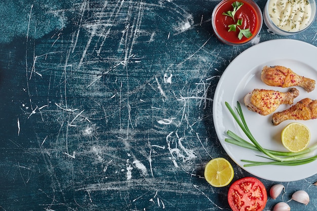 Coscia di pollo piccante fritta in un piatto bianco con il limone.