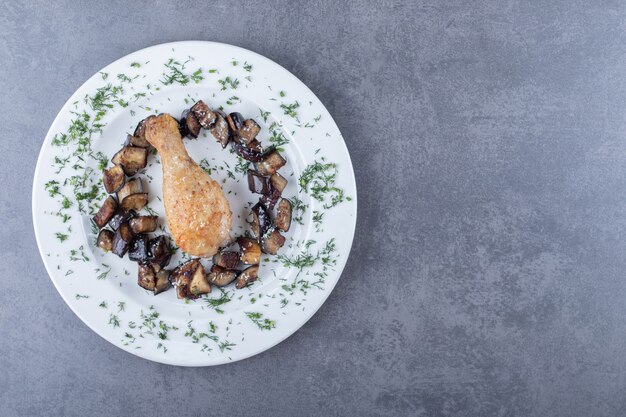 Coscia e melanzane di pollo fritte sul piatto bianco.