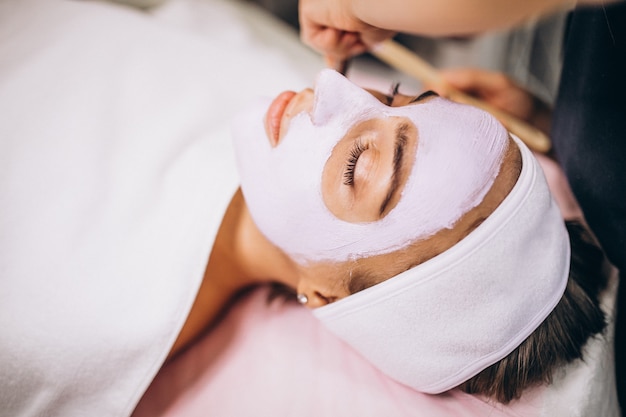 Cosmetologo che applica maschera su una faccia del cliente in un salone di bellezza