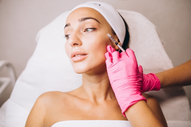 Cosmetologo facendo iniezioni su una faccia di una donna in un salone di bellezza