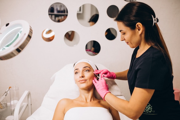 Cosmetologo facendo iniezioni su una faccia di una donna in un salone di bellezza