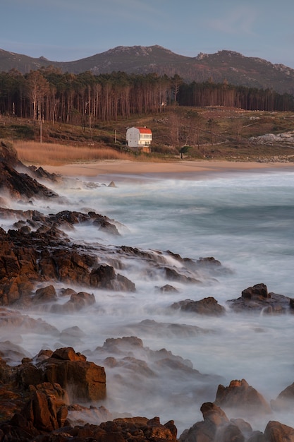 Costa con pietre sulla riva durante il tramonto