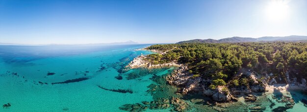 Costa del Mar Egeo con acqua blu trasparente, vegetazione intorno, rocce, cespugli e alberi, vista dal fuco, Grecia