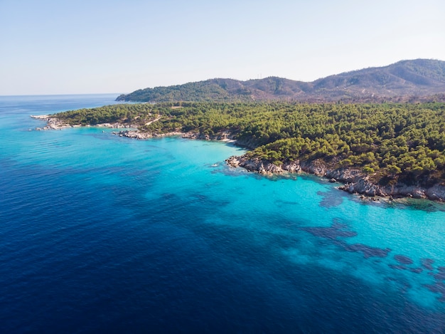 Costa del Mar Egeo con acqua blu trasparente, vegetazione intorno, rocce, cespugli e alberi, vista dal fuco, Grecia