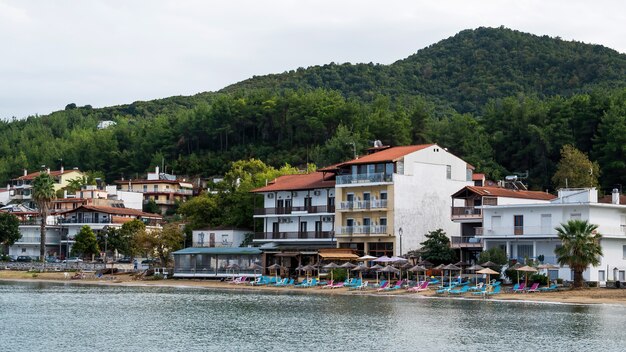 Costa del Mar Egeo, ombrelloni e lettini in spiaggia, edifici in fila