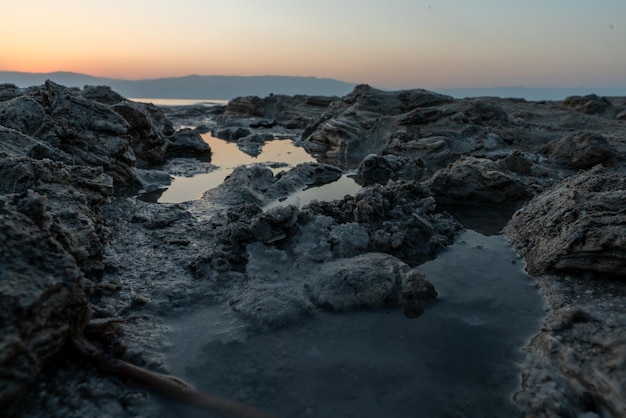 Costa rocciosa circondata dal mare e dalle colline durante l'alba al mattino