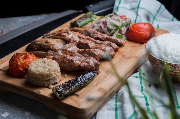 Costole di kebab vista laterale con verdure fritte e cipolla tritata e ayran e coltello nel tagliere