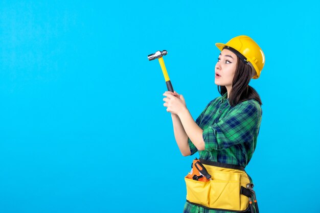 Costruttore femminile di vista frontale in uniforme che tiene martello sul blu