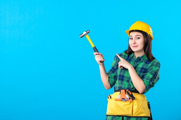 Costruttore femminile di vista frontale in uniforme che tiene martello sul blu