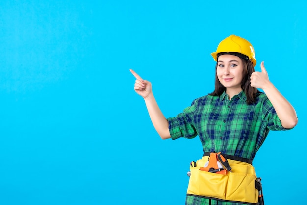 Costruttore femminile di vista frontale in uniforme e casco che sorride sul blu