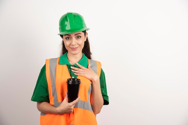 Costruttore femminile sorridente con la tazza nera. Foto di alta qualità