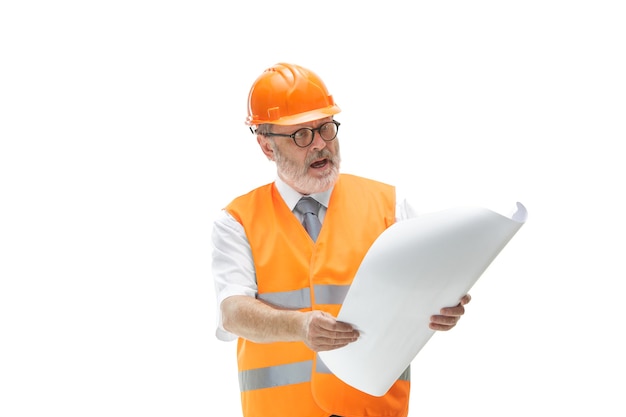 costruttore in un giubbotto di costruzione e casco arancione in piedi su sfondo bianco.