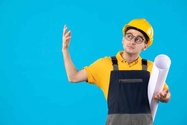 Costruttore maschio vista frontale in uniforme con piano di carta sul blu