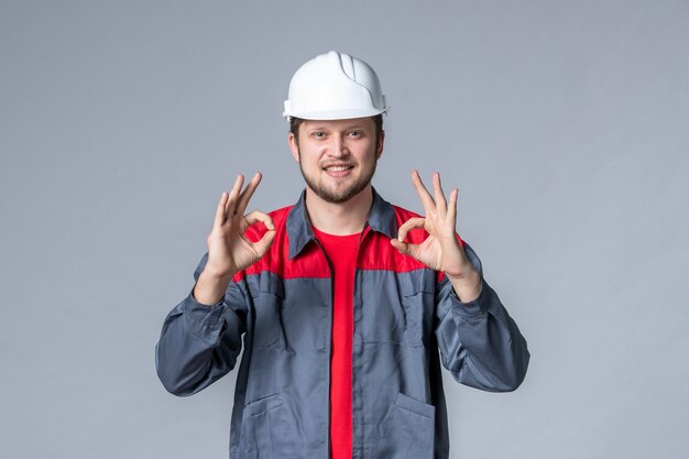 costruttore maschio vista frontale in uniforme e casco su sfondo grigio