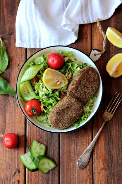 cotoletta di manzo con insalata di verdure fresche in ciotola di metallo