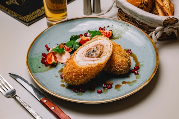 Cotoletta di pollo di vista laterale con melograno e salsa di verdure di pomodoro su un piatto