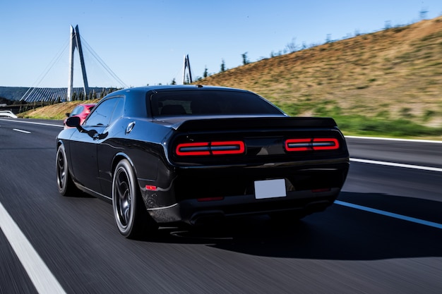 Coupé sportivo nero guida con luci rosse posteriori accese.