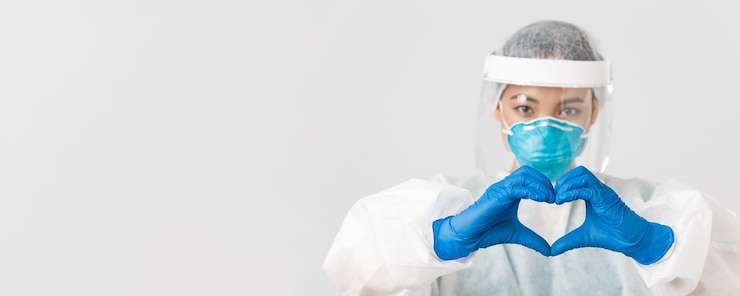 Foto gratuito covid-19, malattia da coronavirus, concetto di operatori sanitari. primo piano di una dottoressa asiatica sicura e premurosa in dispositivi di protezione individuale, che mostra il gesto del cuore ai pazienti.