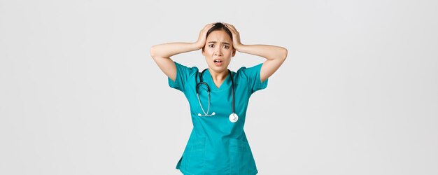 Covid-19, operatori sanitari e prevenzione del concetto di virus. L'infermiera asiatica angosciata e sotto pressione, stagista afferra la testa in preda al panico e fa una smorfia, sentendosi ansiosa, ha un grosso problema.