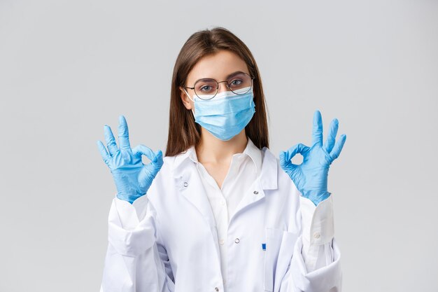 Covid-19, prevenzione di virus, salute, operatori sanitari e concetto di quarantena. Medico professionista, medico in dispositivi di protezione individuale, maschera medica e guanti, mostra segno ok, garanzia