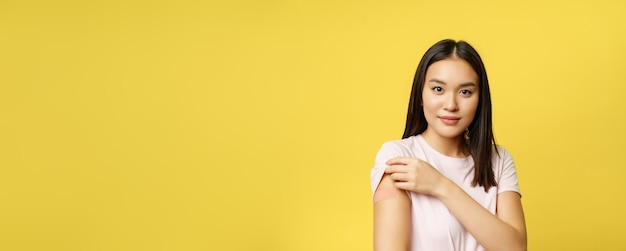 Covid e il concetto medico sanitario sorridente ragazza coreana mostra la spalla con la toppa ha preso il colpo di coro