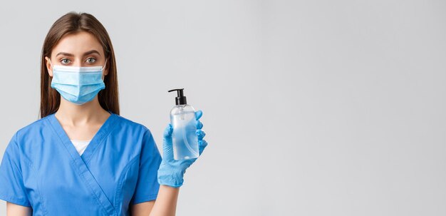 Covid19 prevenzione del virus del concetto di operatori sanitari Giovane dottoressa infermiera piuttosto professionale in maschera medica e scrub che mostra disinfettante per le mani o sapone per proteggere dal coronavirus