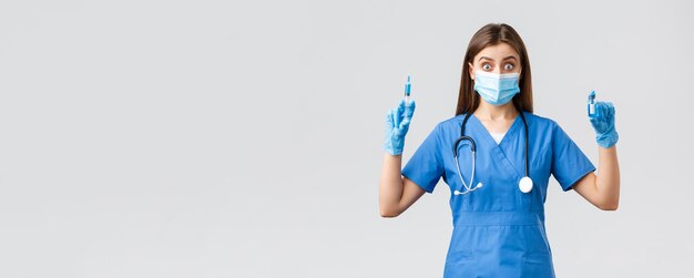 Covid19 prevenzione del virus operatori sanitari sanitari e concetto di quarantena Eccitata infermiera in blu scrub medico in clinica che tiene siringa e fiala con vaccino contro il coronavirus