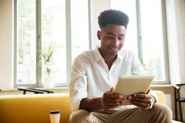 Coworking di seduta del giovane uomo africano allegro