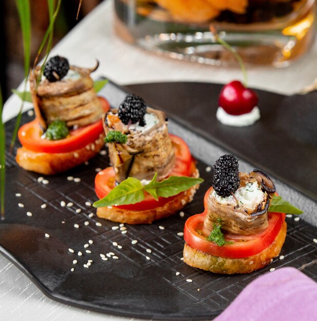 Cracker con fettine di pomodoro, involtini di melanzane e frutti di bosco.