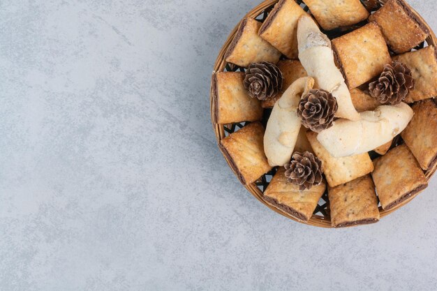 Cracker e biscotti in una ciotola con pigne. Foto di alta qualità