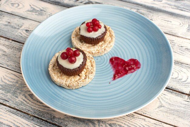 cracker e torta con mirtilli rossi in cima all'interno del piatto blu su grigio