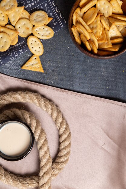 Cracker salati con vista in lontananza superiore con latte e corde sulla foto di spuntino croccante di sfondo grigio