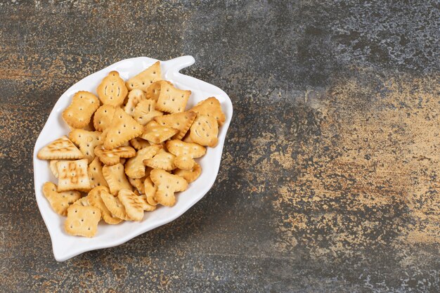 Cracker salati di varie forme su piatto a forma di foglia.