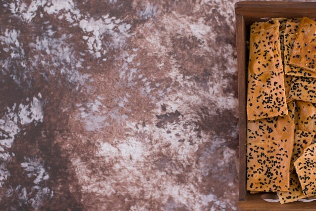 Crackers con cumino nero sopra in vassoio di legno sul lato destro.