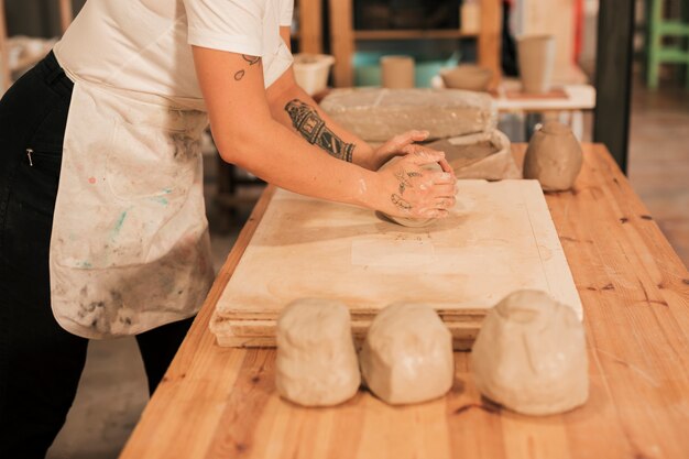 Craftswoman che impasta l&#39;argilla sul bordo di legno sopra la tavola