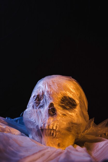 Cranio in sacchetto di plastica illuminato da luce arancione e blu